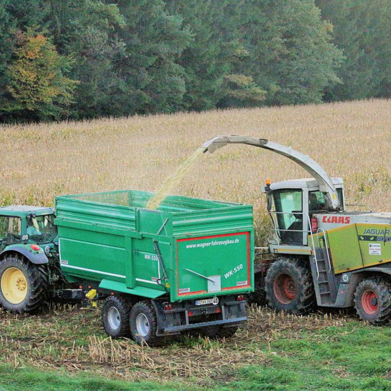 Traktoren fahren auf dem Feld die Ernte ein