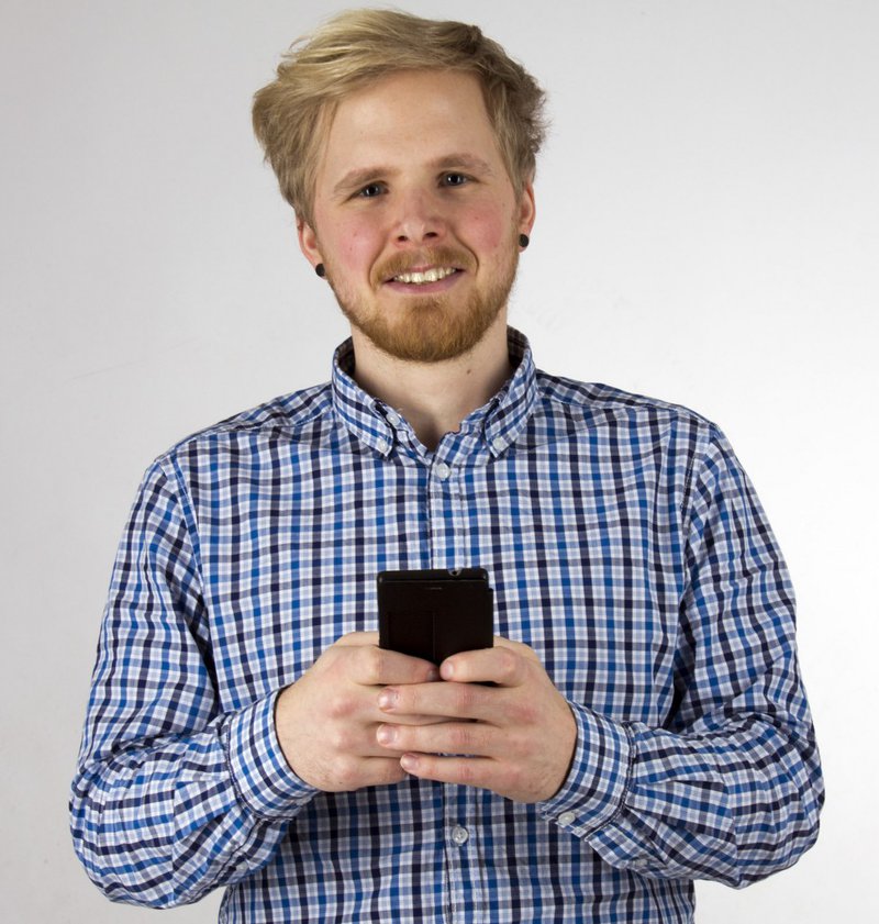 Ein Mann in blau-kariertem Hemd hält sein Smartphone in den Händen.