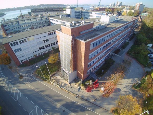Zwei nebeneinander stehende Universitatsgebäude, an der Front des einen sind mehrere Solarplatten angebracht.