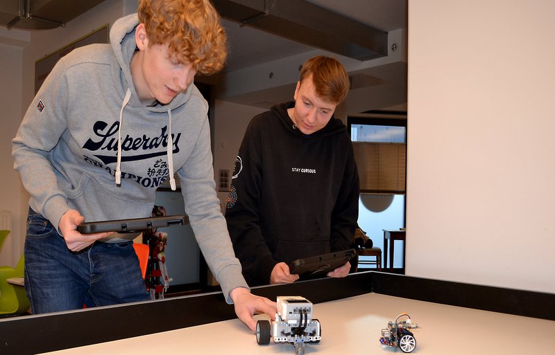 Zwei Schüler beim Umgang mit einem Roboter