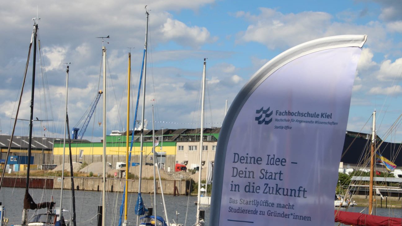 Flagge des StartUp Office der FH Kiel vor Segelschiffen
