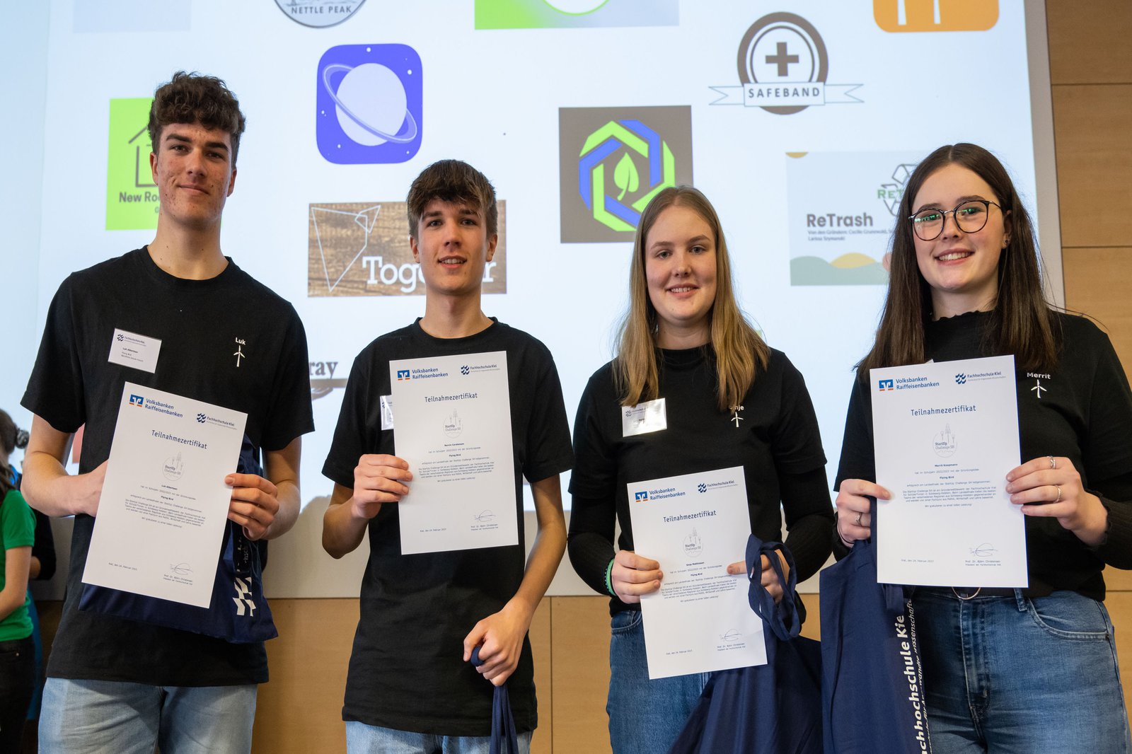 vier Schüler*innen stehen mit Urkunden vor ihrer Präsentation bei der StartUp Challenge SH 2023