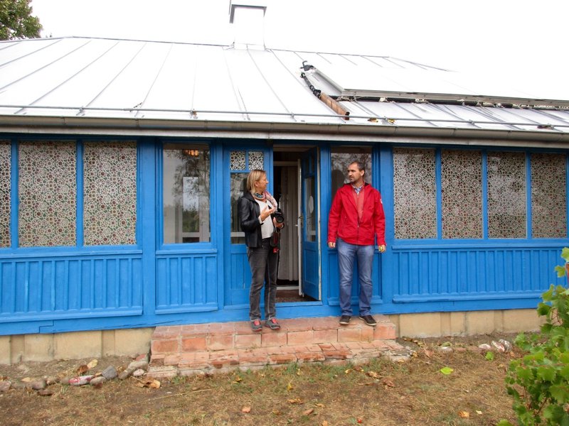 Ein Mann und eine Frau stehen vor einem flachen blauen Haus.