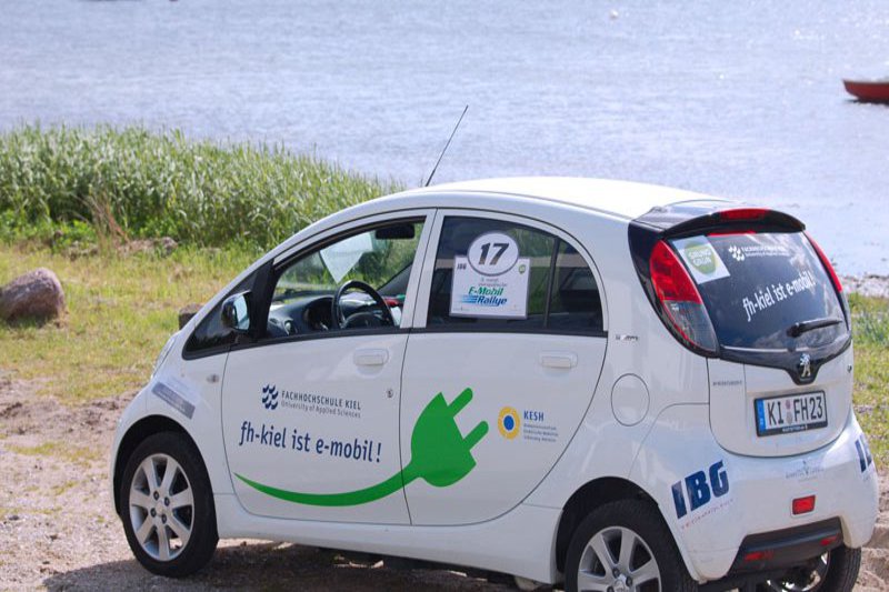 Ein E-Auto parkt Nahe einem Strand.