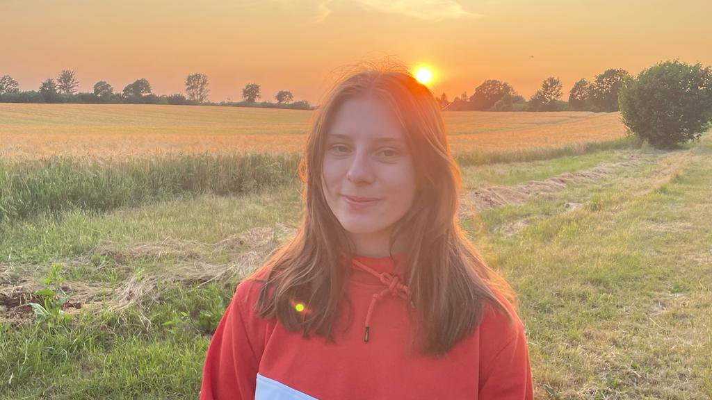Eine Frau steht bei Abendsonne auf einem Feld