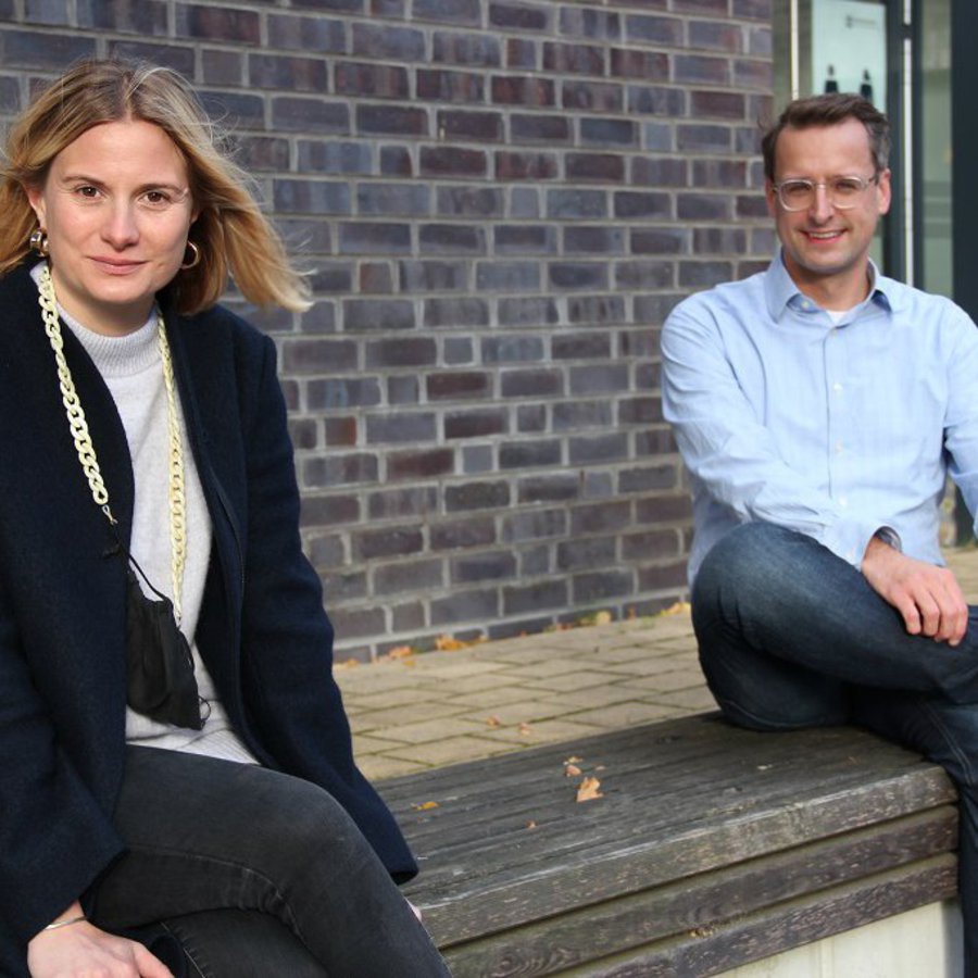 Alexa Magssam und Tobias Hochscherf sitzen auf einer Bank vor dem neuen Seminargebäude.