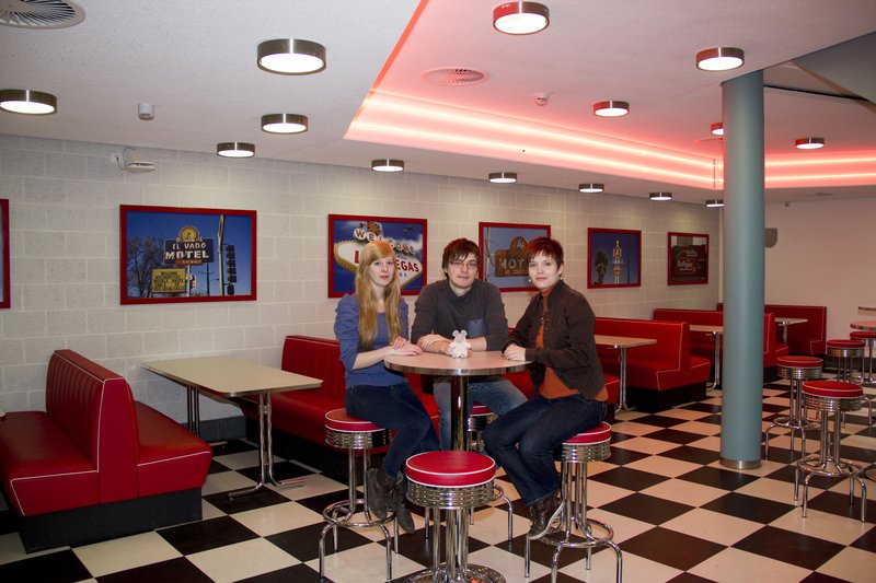 Zwei Frauen und ein Mann sitzen an einem Tisch, im American Diner der FH Kiel.