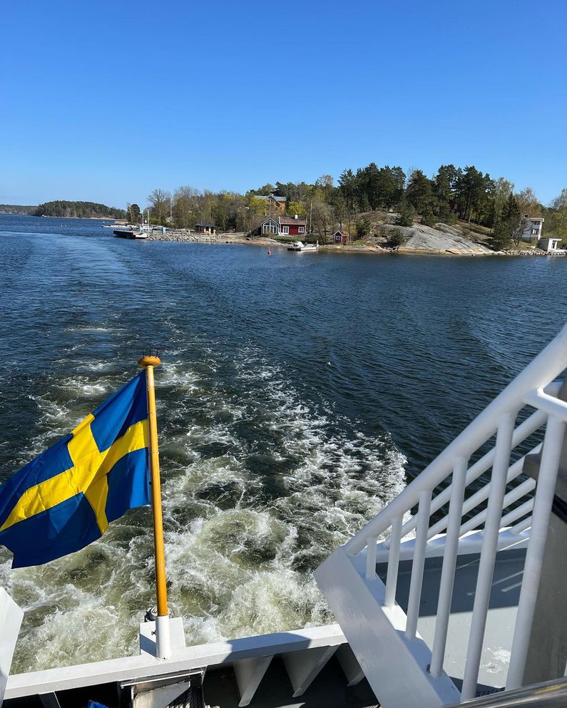 Boot auf einem Fjord, es weht die schwedische Flagge in blau und gelb