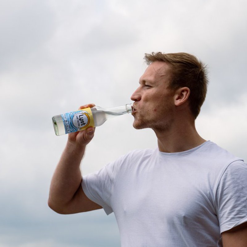 Maurice Kusza trinkt aus einer Flasche Lyst Hard Seltzer. Foto: Kim-Naja Kaufner. 