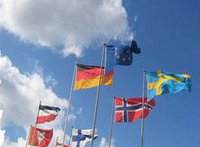 sieben Nationalflaggen wehen im Wind, darüber Wolken