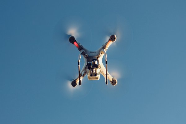 Ein am wolkenlosen blauen Himmel fliegende Drohne.
