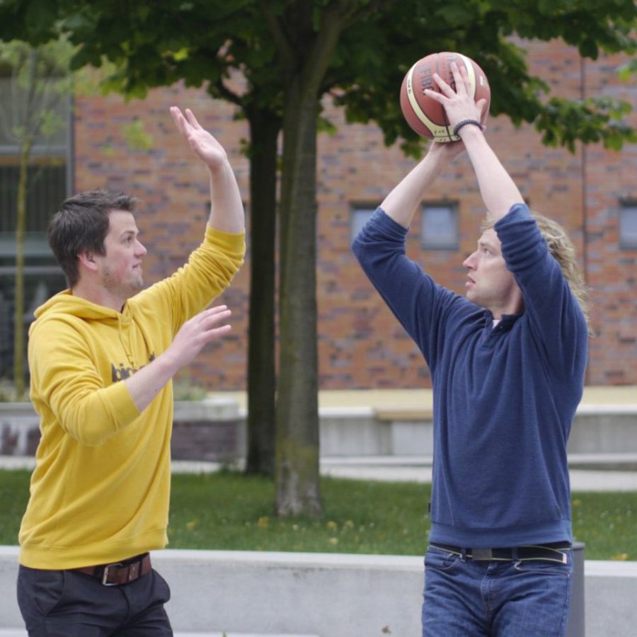 Zwei Studenten die mit einem Basketball spielen.