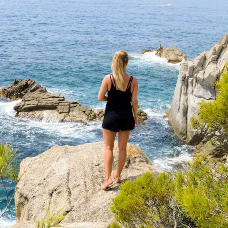 Frau auf felsiger Klippe am Wasser