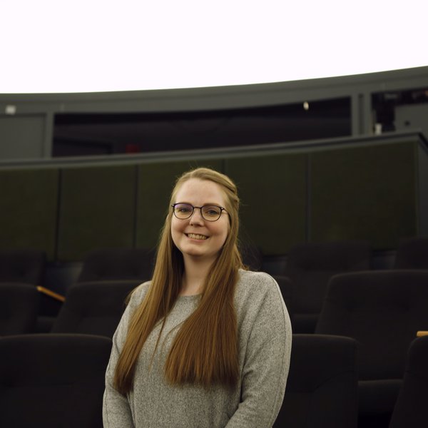 Cora Braun steht in einem Planetarium