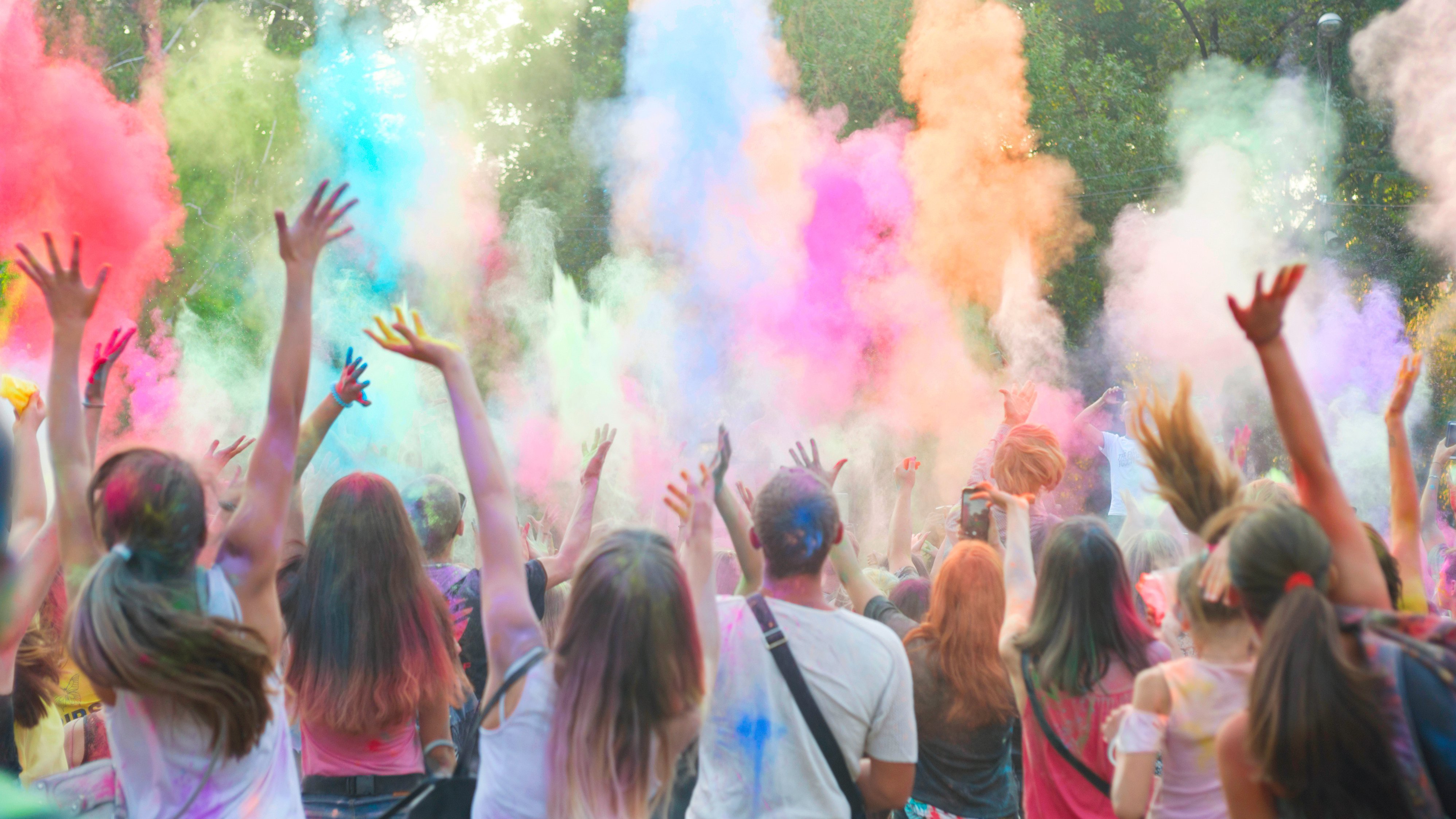 eine Gruppe von Menschen wirft buntes Farbpulver beim Holi-Festival in die Luft