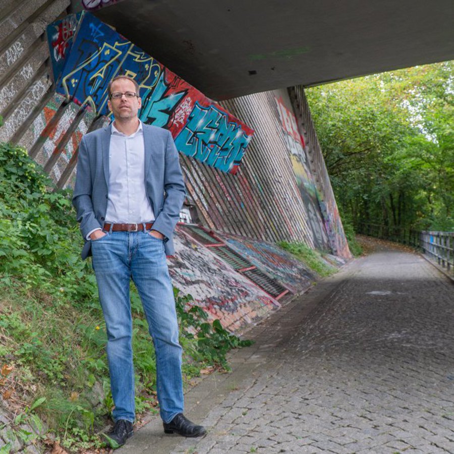 Prof. Dr.-Ing. Stephan Görtz steht vor dem Pfeiler einer Autobrücke.