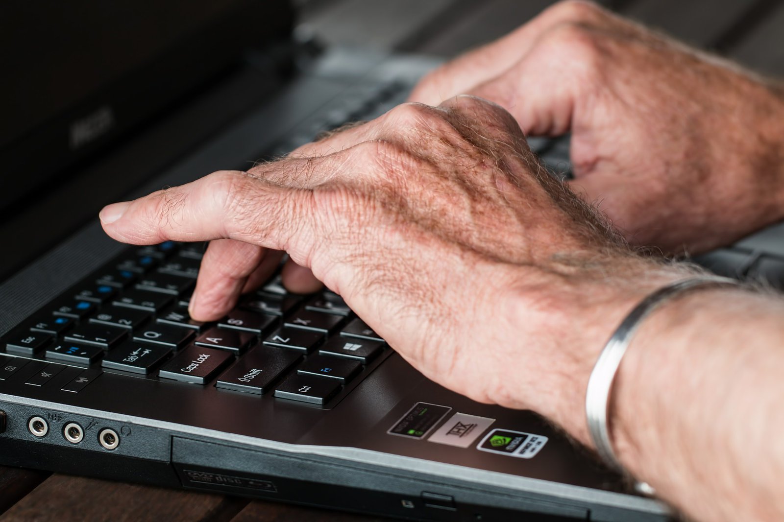 Zwei männliche Hände über der Tastatur eines Laptops.