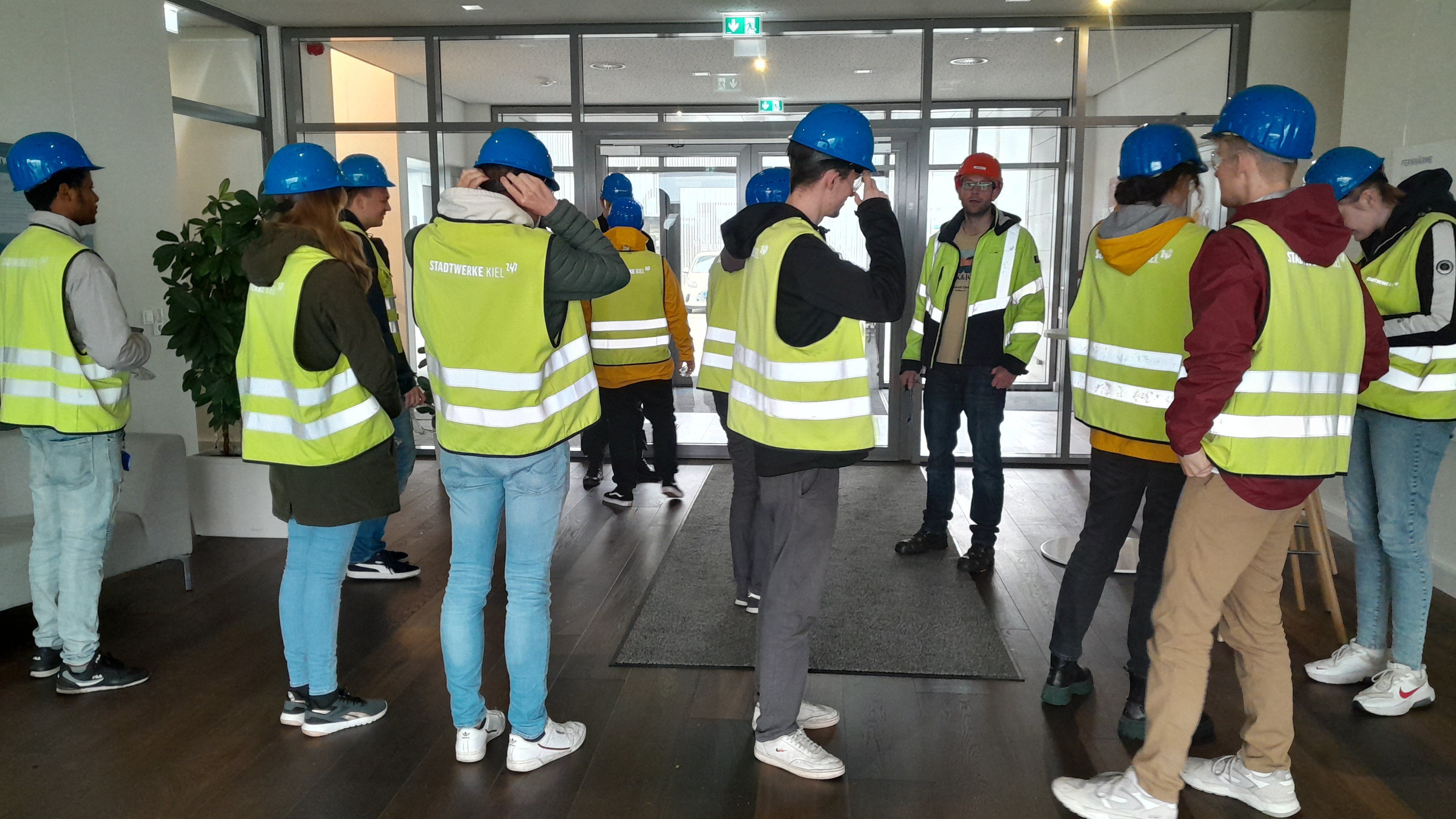 FH-Studierende statten sich mit Warnwesten und Schutzhelmen für den Rundgang im Küstenkraftwerk Kiel aus