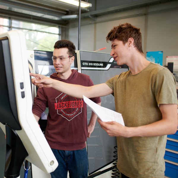 Zwei Männer bedienen eine Maschine in der Werkstatt