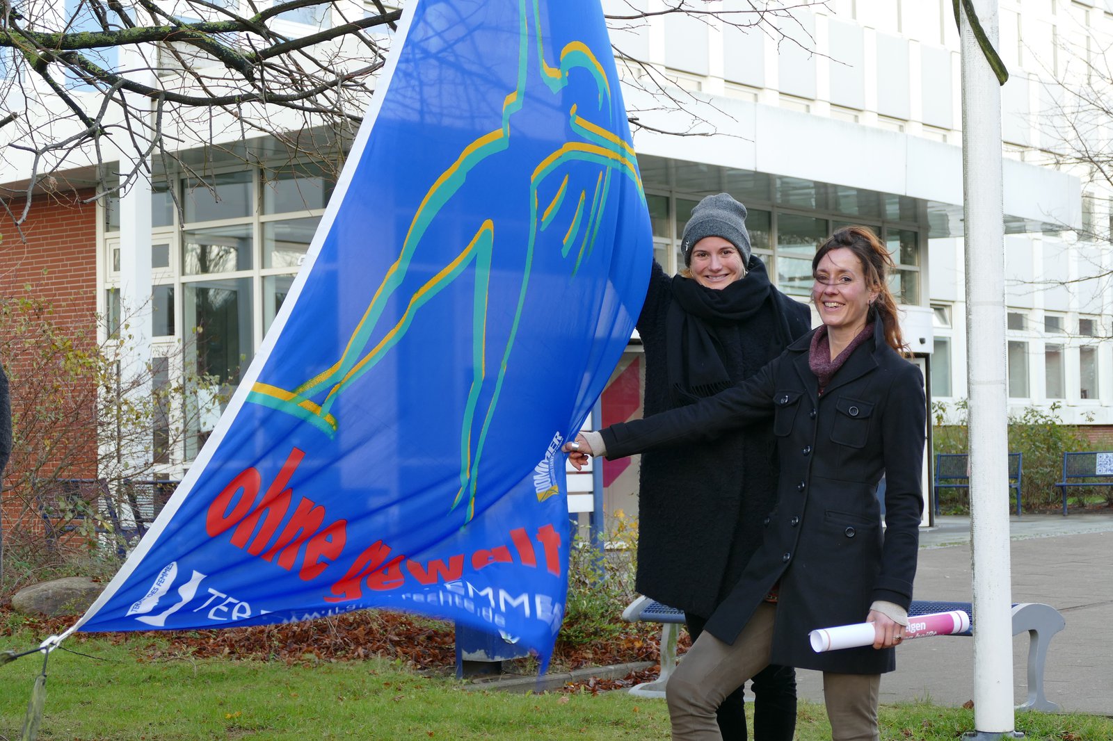 Wei Frauen präsentieren eine blaue Fahne.