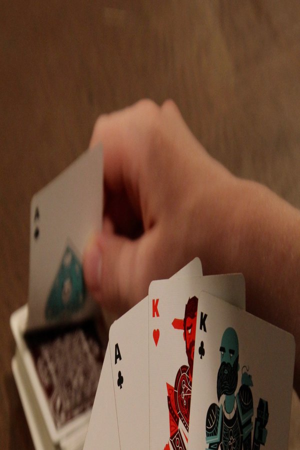 Jemand hält Spielkarten in der Hand, daneben liegen Pokerchips.