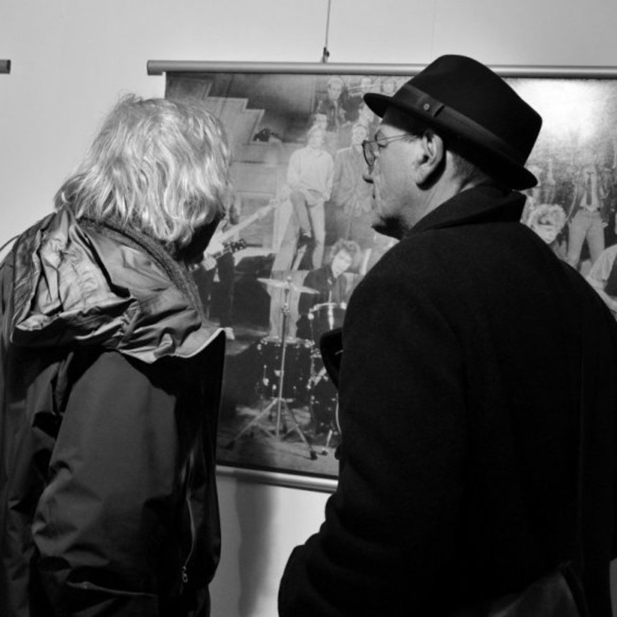 Das Schwarz-Weiss-Foto zeigt zwei Männer, die sich ein Werk von nahem anschauen.