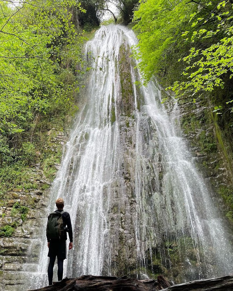 Tim steht vor einem meterhohen Wasserfall