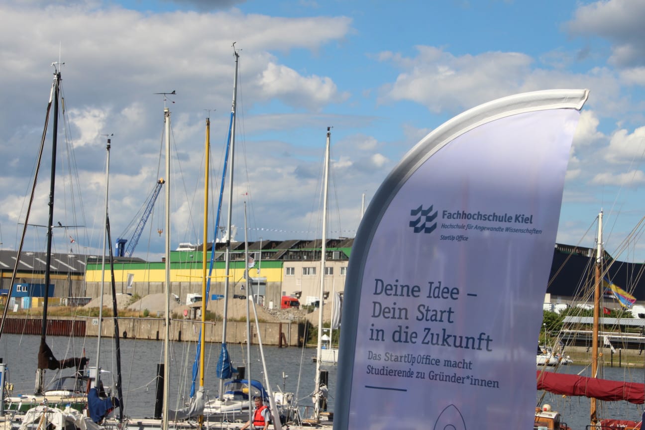 Flagge des StartUp Office der FH Kiel vor Segelschiffen