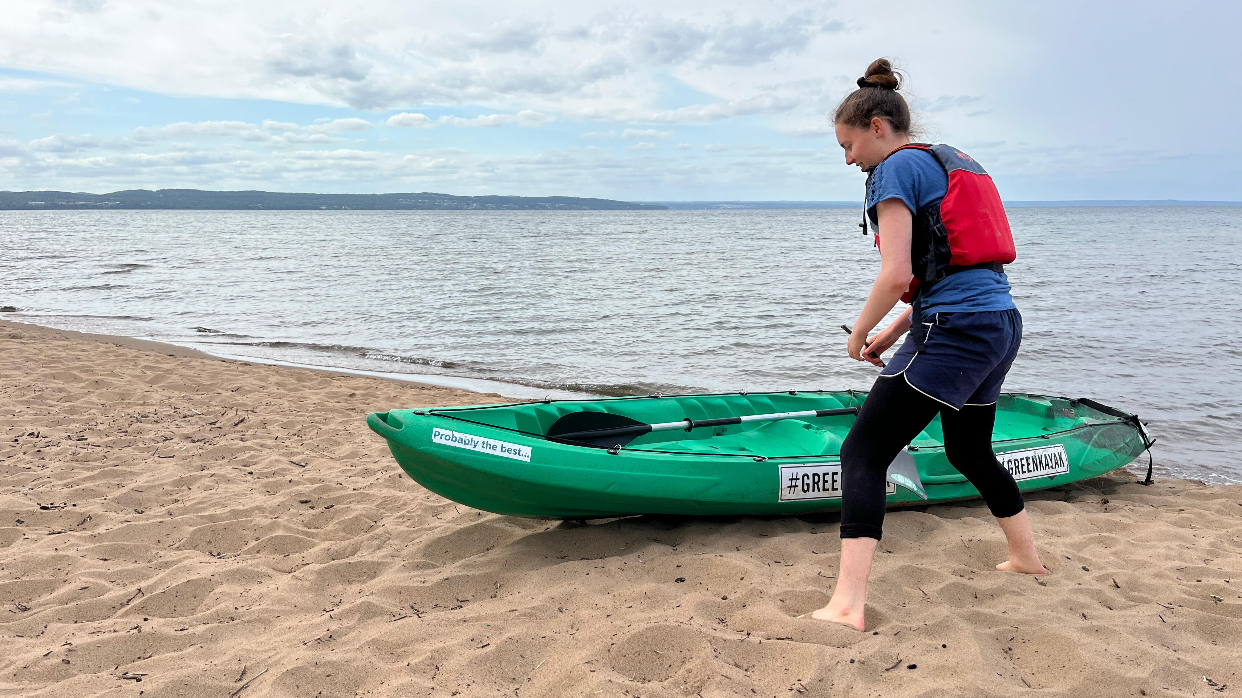 eine Frau an einem Kajak am Strand