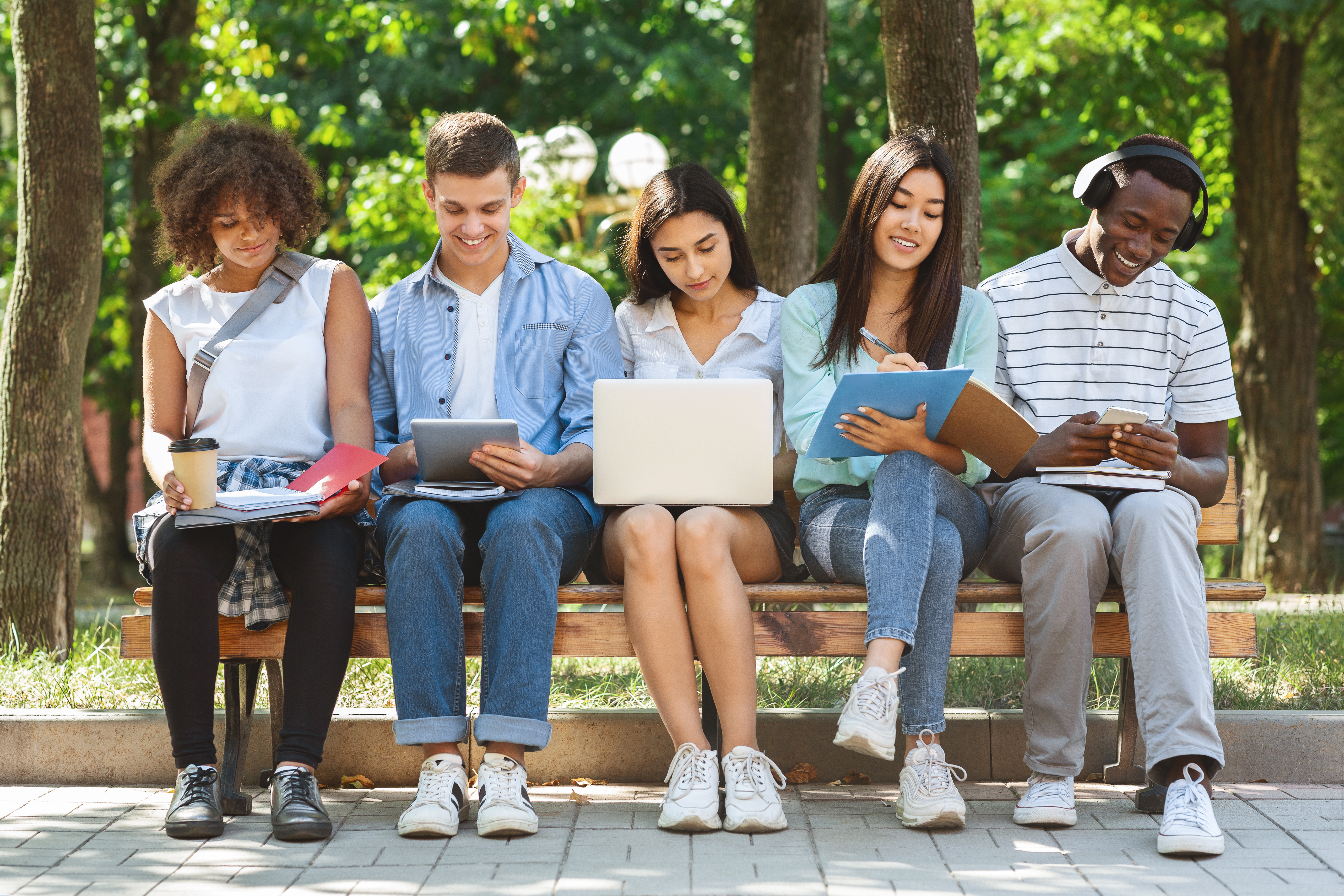 Group of students with laptop and tablet computer studying toget eine Gruppe junger Menschen auf einer Bank