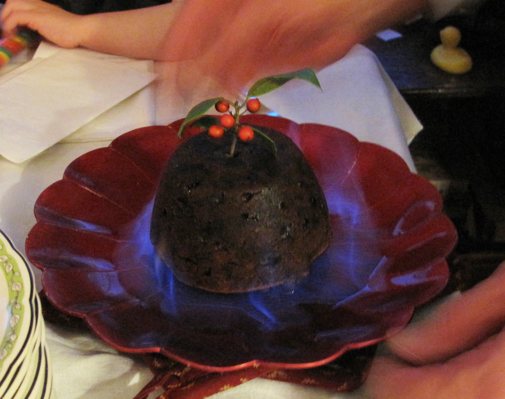Ein dunkler Pudding, angerichtet auf einem dunkel roten Teller.