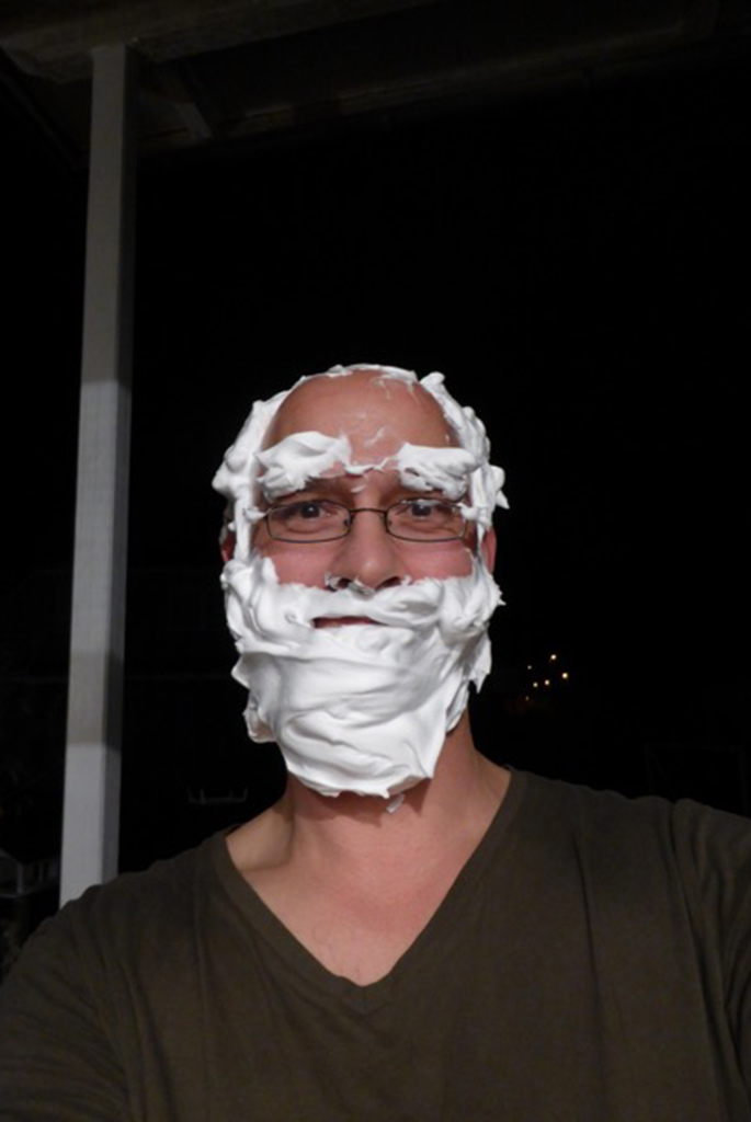 Ein Mann mit Rasierschaum in seinem Gesicht und am Kopf. Er sieht ansatzweise aus wie ein Weihnachtsmann.