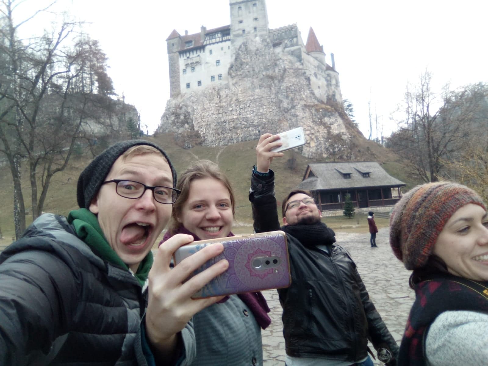 Eine Gruppe Studierender albert rum und schiesst Selfies. Im Hintergrund ist eine alte Steinburg zu sehen.