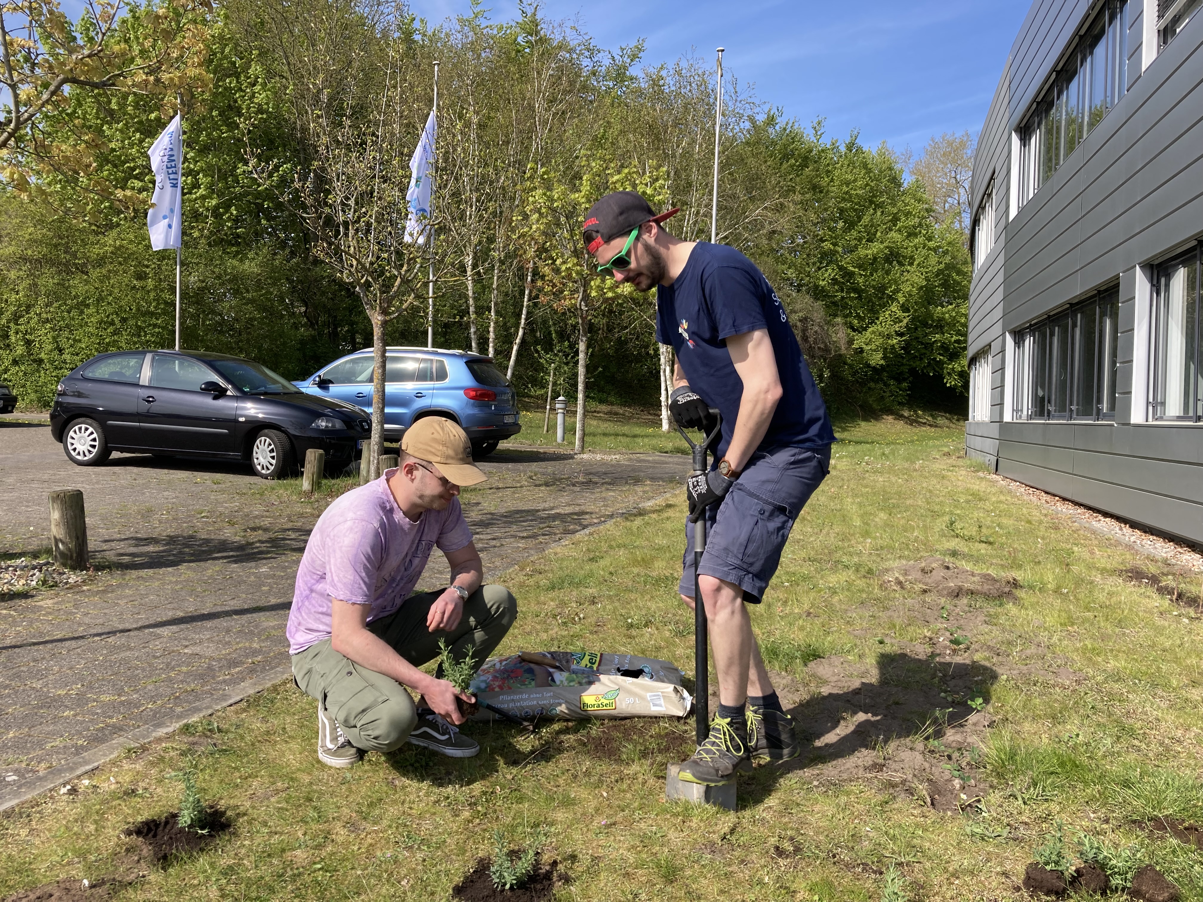 Studenten Ole Diercks und Daniel Terhorn mit Spaten und Pflanzen auf dem Rasen