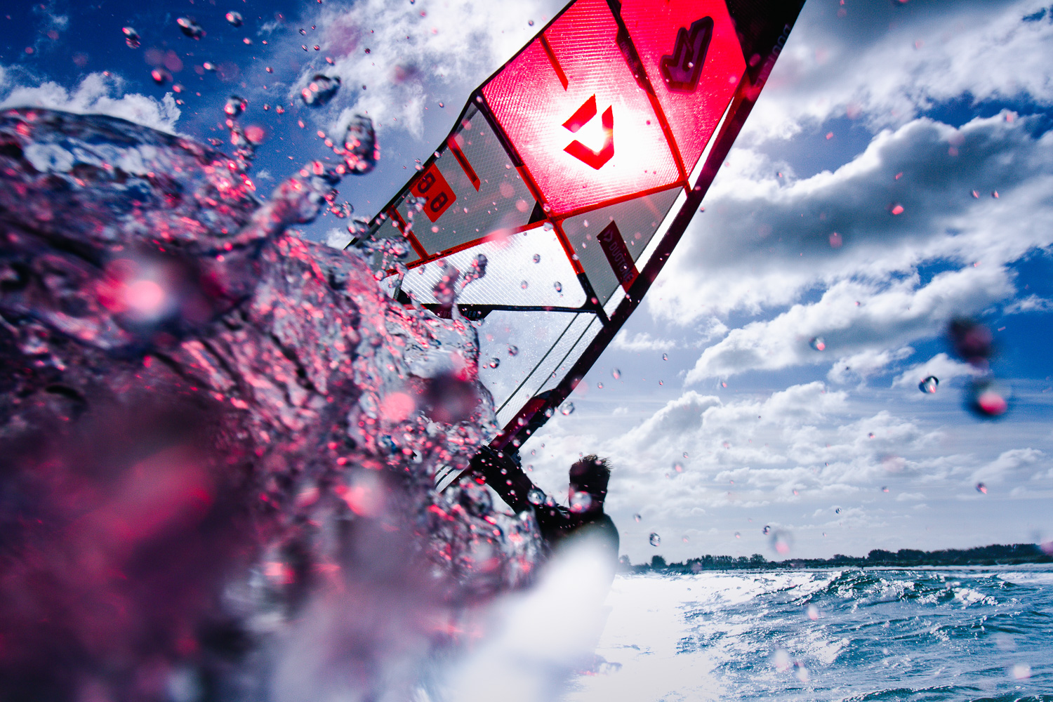 Ein Windsurfer, aufgenommen von einer Kamera die an der Spitze des Bretts befestigt ist. Wasser Tropfen machen die Aufnahme zu einer besonderen Momentaufnahme.