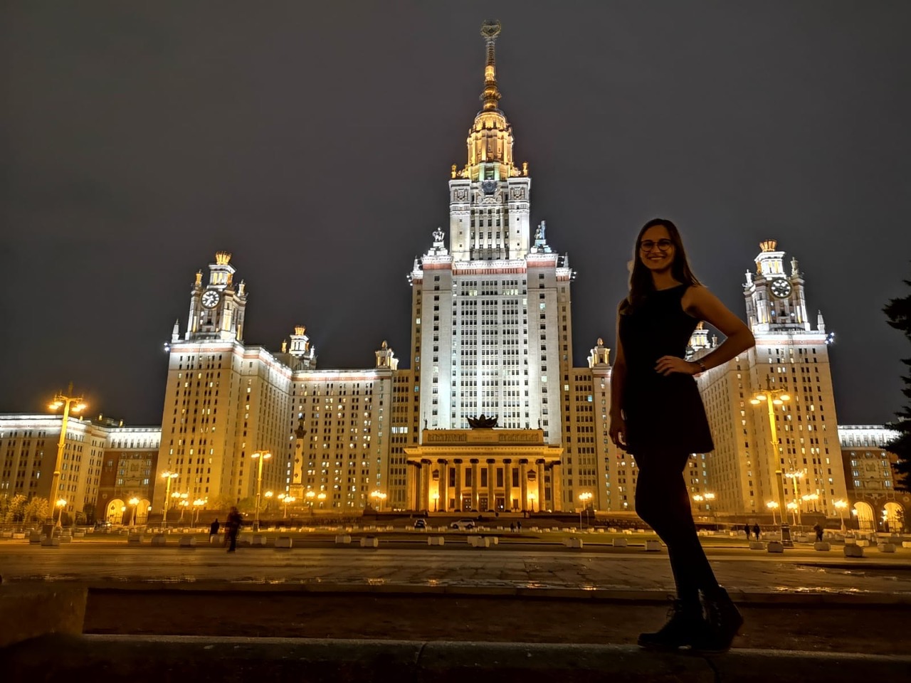 Eine Studentin posiert vor einem breit illuminierten Gebäude in Moskau.