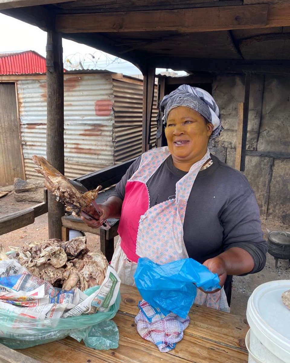 Frau auf einem Markt in Port Elizabeth. Es wird gekochtes Schaf am Straßenrand verkauft