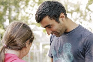 Ein Mann in grauem T-Shirt und ein Mädchen mit pinker Jacke, stehen zusammen  im Freien.