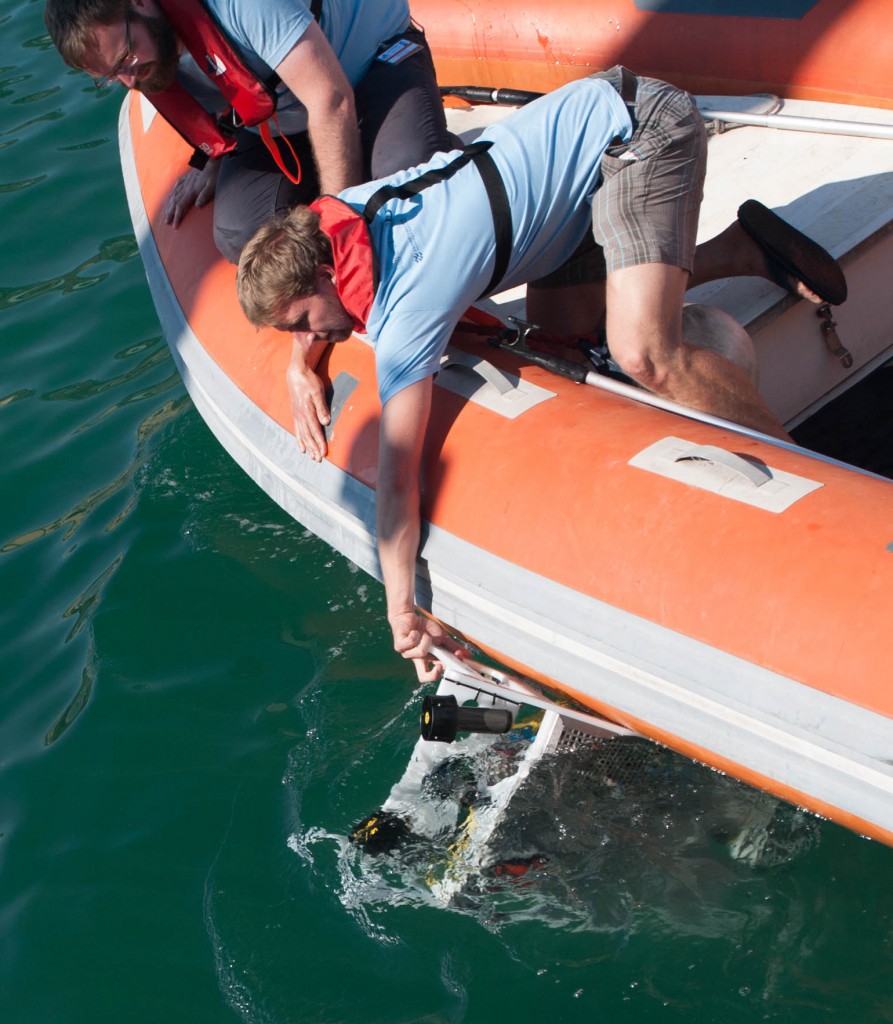 Ein Mann setzt von einem Schlauchboot aus eine Maschine ins Meer.