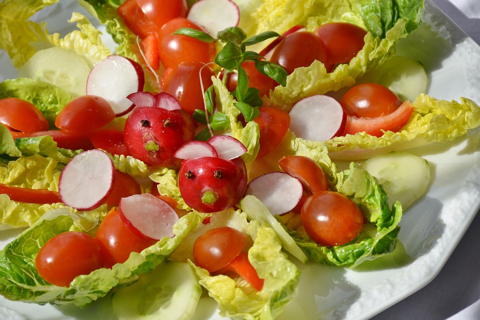 Häppchen bestehend aus Römersalatblättern, agerichtet mit Tomaten und Radieschen.