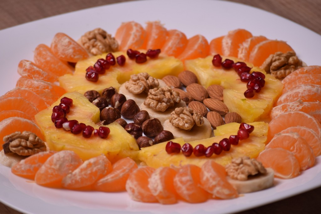 Auf einem Teller sind Früchte und Nüsse angerichtet.