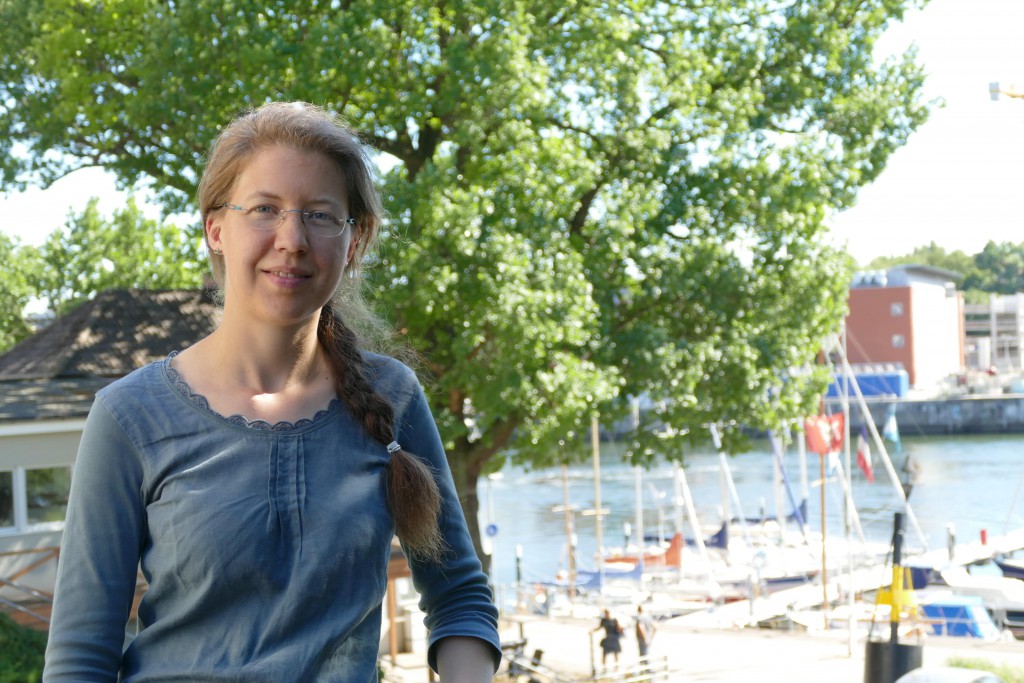 Eine Frau posiert auf einer Anhöhe, im Hintergrund ist unten ein Yachthafen zu sehen.