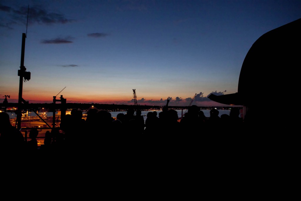 Die Silhouette einer Menschenmenge umgeben von dem dumpfen Licht des Sonnenuntergangs.