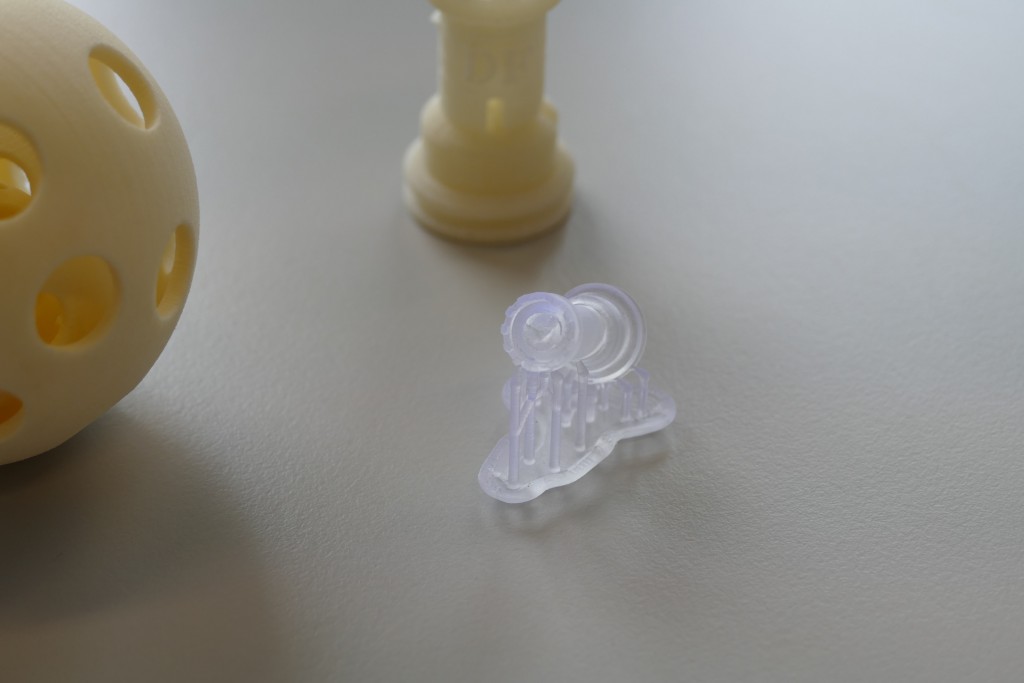 Drei aus dem 3D-Drucker stammende  Gegenstände. Zwei von ihnen sind eher gelblich, einer von ihnen ist nahe zu weiss-transparent.