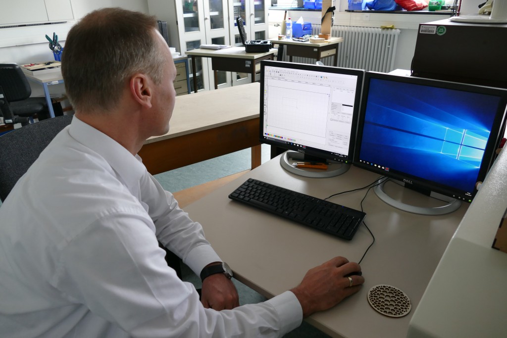 Ein Mann in weissem Hemd sitzt an einem Computer mit zwei Monitoren.