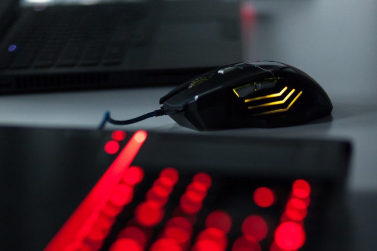 Eine gelb leuchtende Maus, hinter einer rot leuchtenden Laptop-Tastatur.