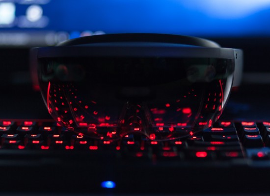 Eine VR-Brille liegt auf einer rot leuchtenden Tastatur.