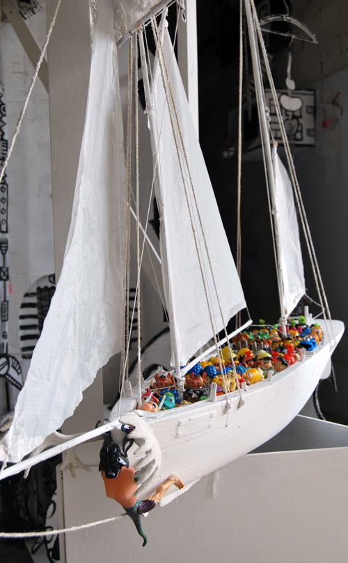 In einem hölzernen, weißen Spielzeugschiff befinden sich viele Spielzeugfiguren.