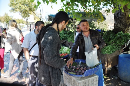 Zwei Männer kaufen etwas Obst bei einem Straßehändler.
