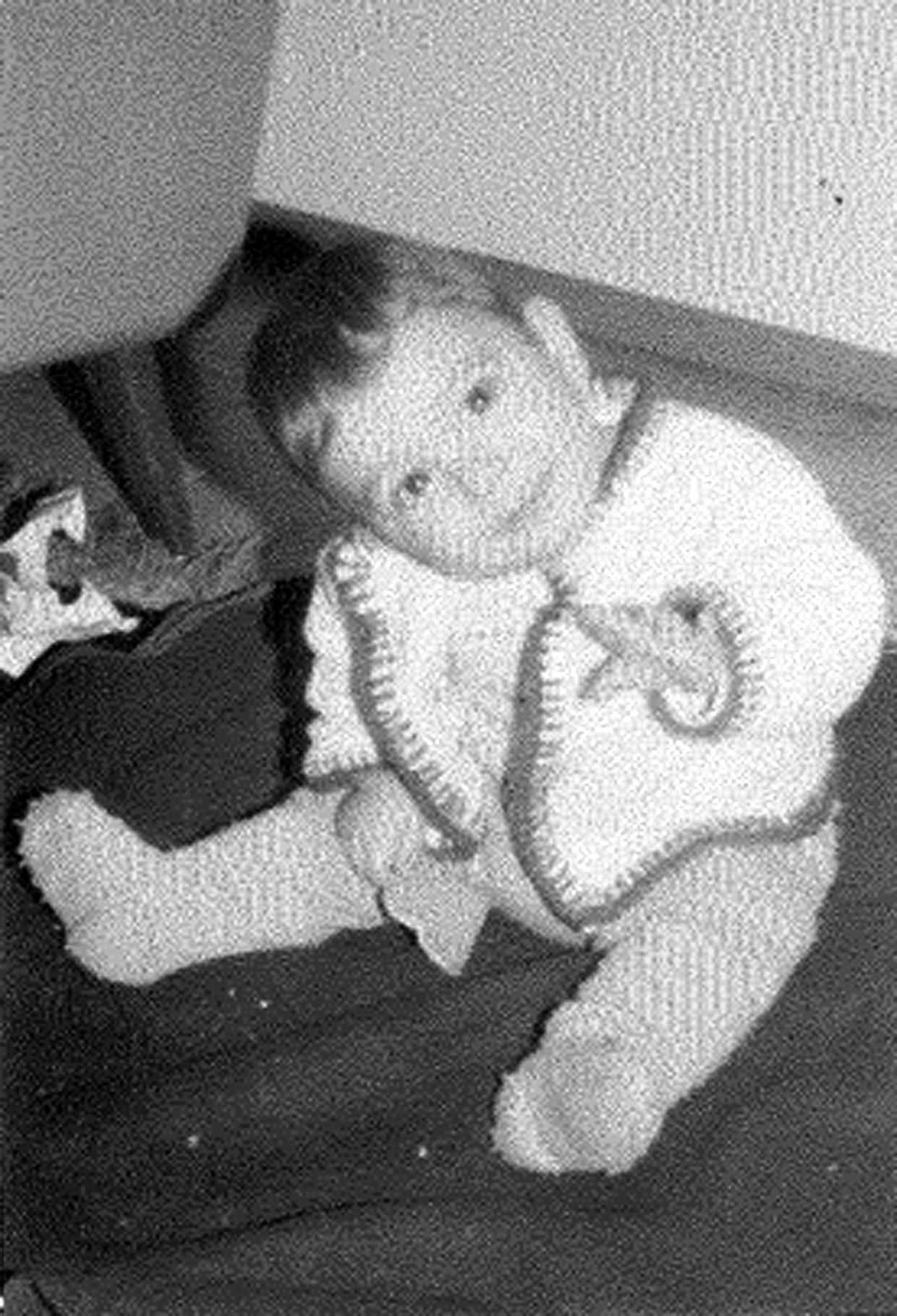 Das Schwarz-Weiss-Foto zeigt ein kleines Kind sitzend und in die Kamera lächelnd.